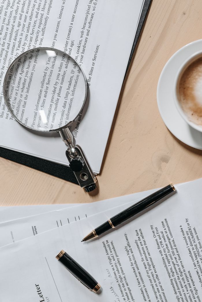about-us-02 Top view of documents with a magnifying glass and pen, ideal for business or legal themes.