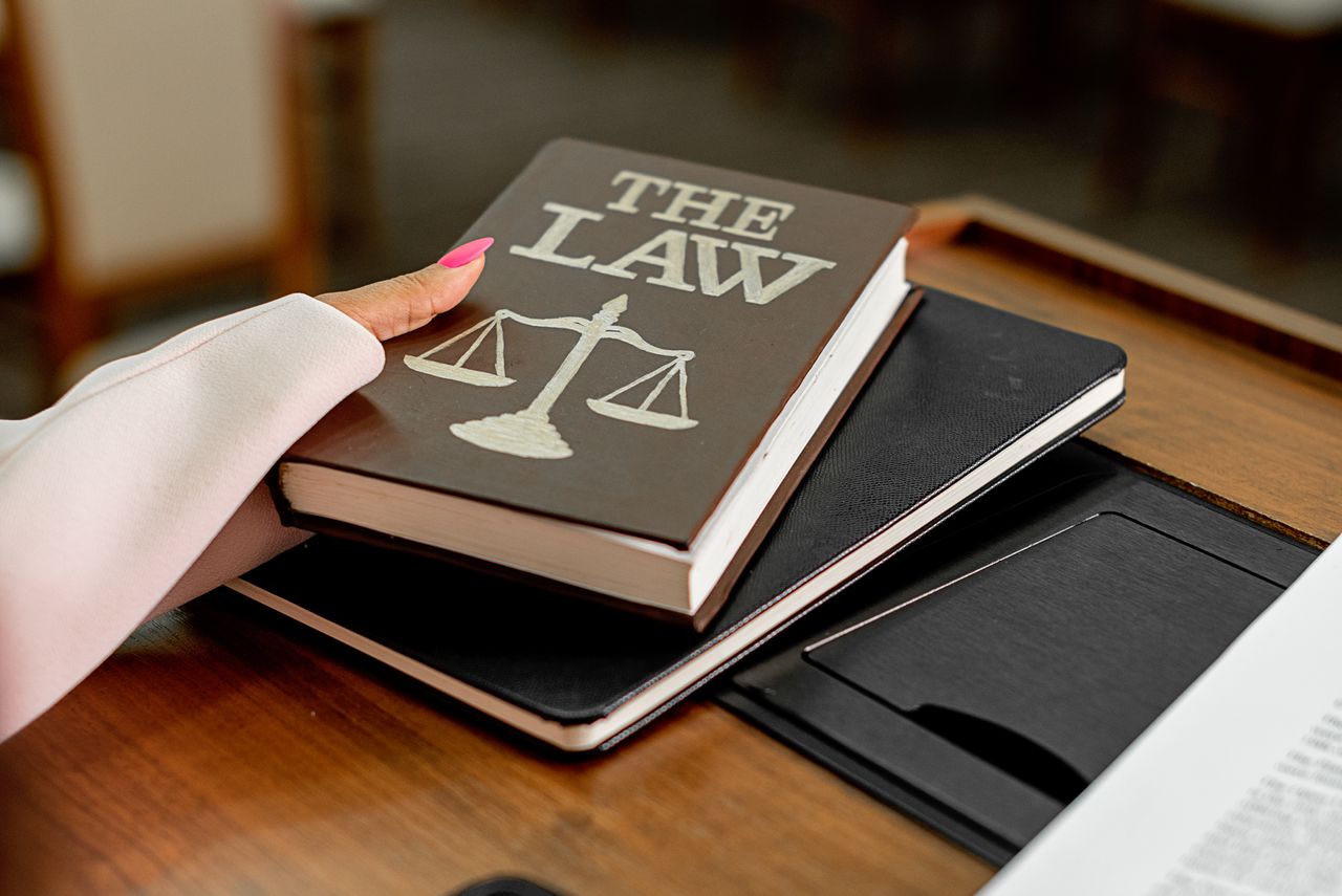 heros-img Closeup image of a law book titled 'The Law' on a wooden desk with scales of justice.